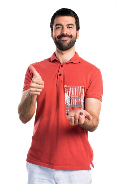 Handsome man holding a supermarket cart toy with thumb up