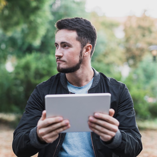 Handsome man holding a tablet and looking away