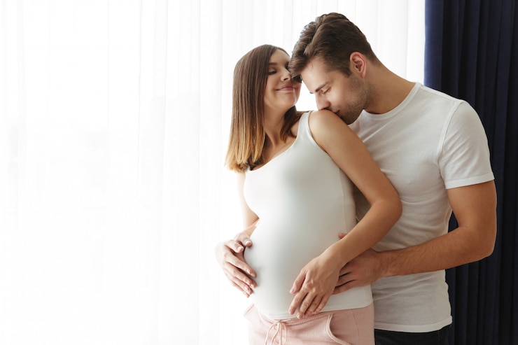 Free Photo handsome man hug his lovely pregnant wife indoors at home