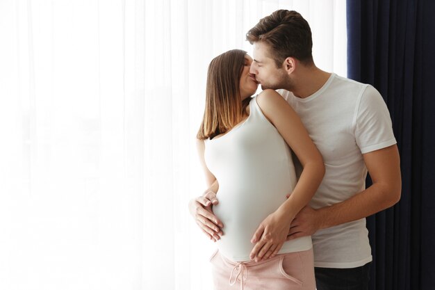 Handsome man hug his lovely pregnant wife indoors at home