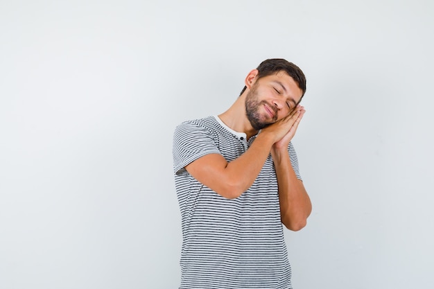 Free photo handsome man leaning on palms as pillow in t-shirt and looking sleepy , front view.