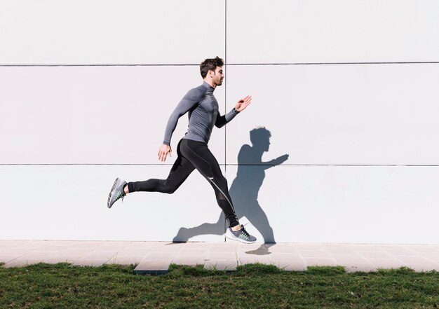 Handsome man leaping near white wall