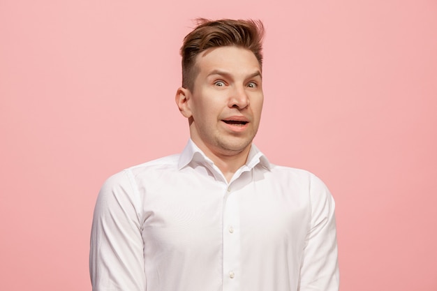 Handsome man looking surprised isolated on pink