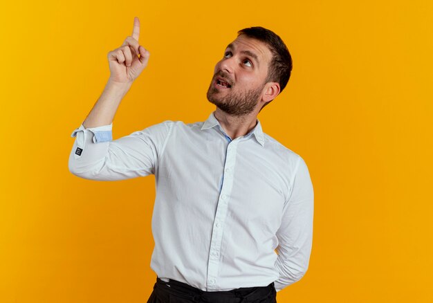 ハンサムな男は、オレンジ色の壁に孤立して見えると上向き