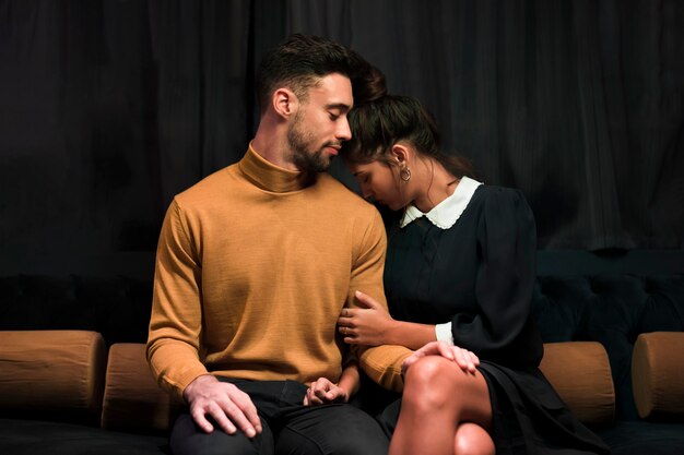 Handsome man near attractive young woman on settee