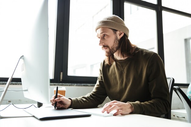 Handsome man in office using computer. Looking aside.