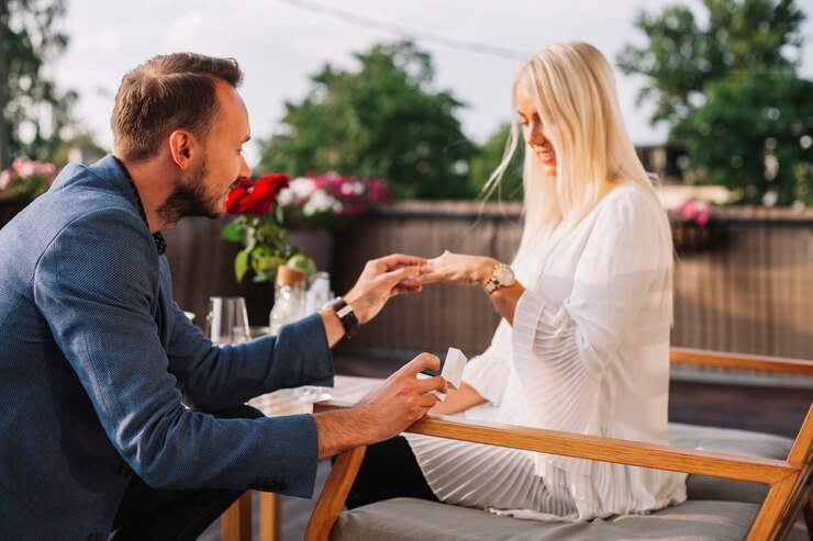 Free Photo handsome man placing wedding ring on blonde woman's hand in the restaurant