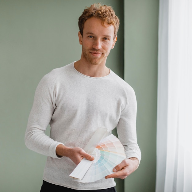 Free photo handsome man planning to redecorate the house using paint palette