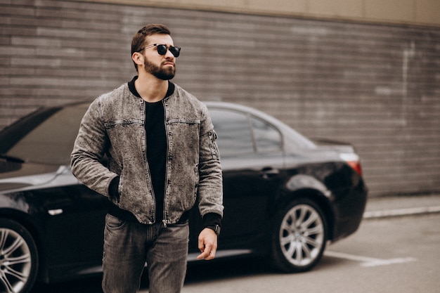 Free photo handsome man posing by the car in the street