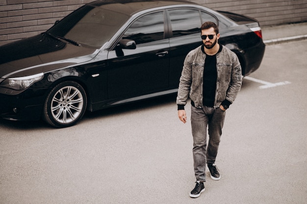 Handsome man posing by the car in the street