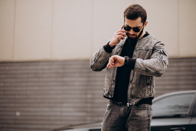 Handsome man posing by the car in the street