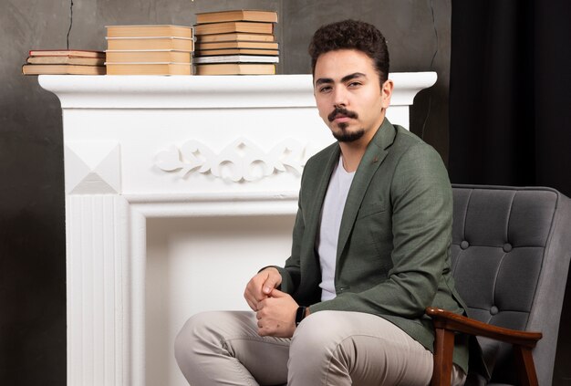 handsome man posing next to fireplace and books