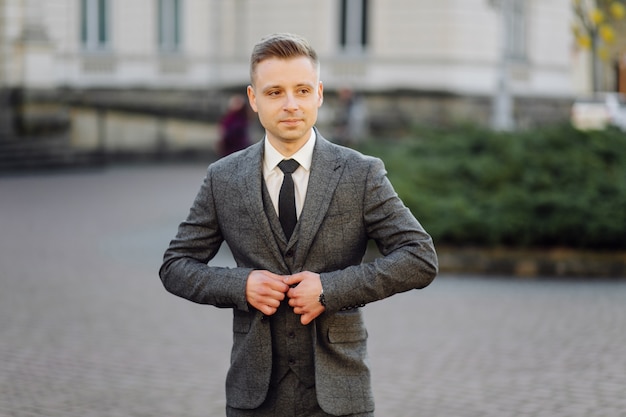 Free photo handsome man posing in wedding suit in the streets