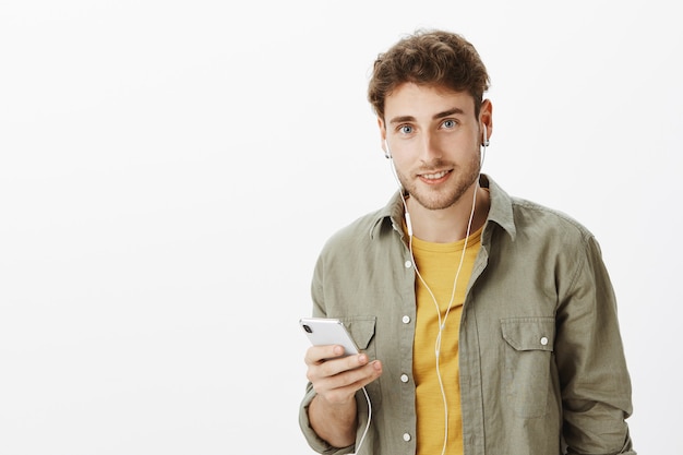 Handsome man posing with smartphone in the studio