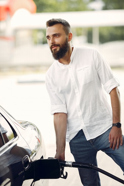 Free photo handsome man pours gasoline into tank of car