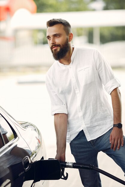 Handsome man pours gasoline into tank of car