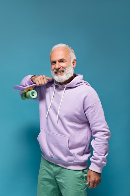 Free photo handsome man in purple hoodie holding longboard