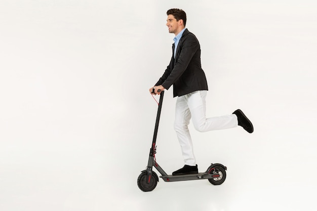 Handsome man riding on electic kick scooter isolated on white studio background