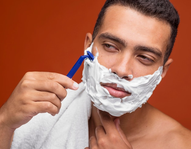 Handsome man shaving his beard with razor