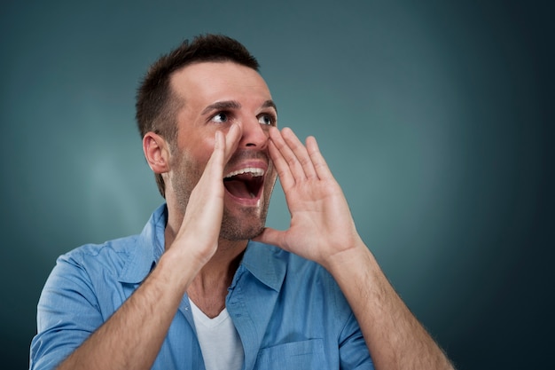 Handsome man shouting through hands
