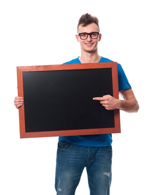 Handsome man showing on empty blackboard