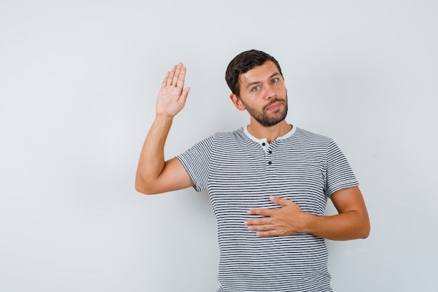 Handsome man showing his palm in t-shirt and looking confident , front view.