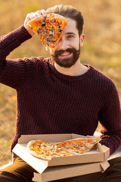 ピザのスライスを示すハンサムな男