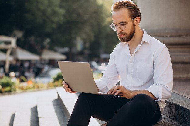 Handsome man sitting on stairs and working on computer