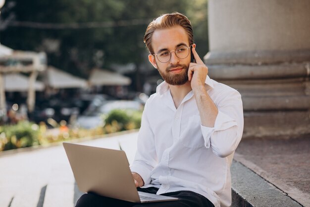 Handsome man sitting on stairs and working on computer