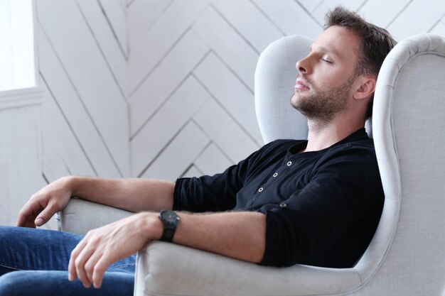 Handsome man sleeping on the armchair