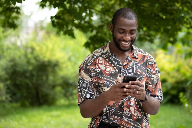 Handsome man spending time outdoors and using modern smartphone