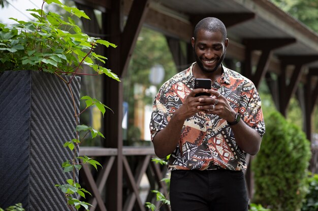 Handsome man spending time outdoors and using modern smartphone