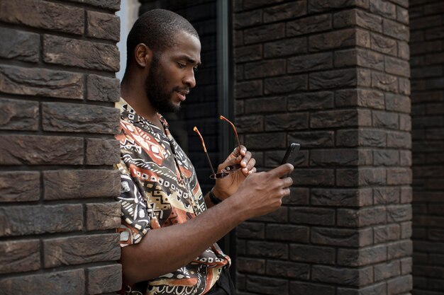 Handsome man spending time outdoors and using modern smartphone