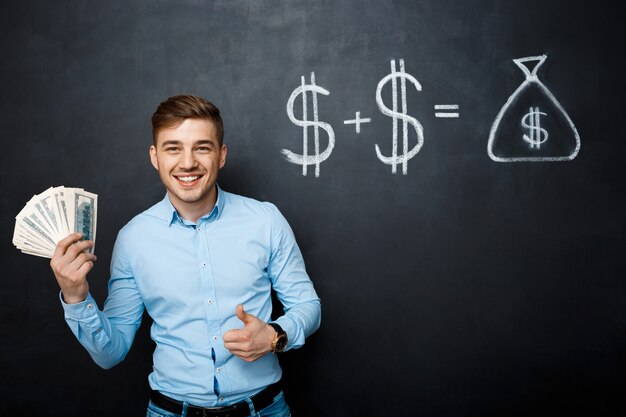 Handsome man standing over blackboard  with drawn dollar concept