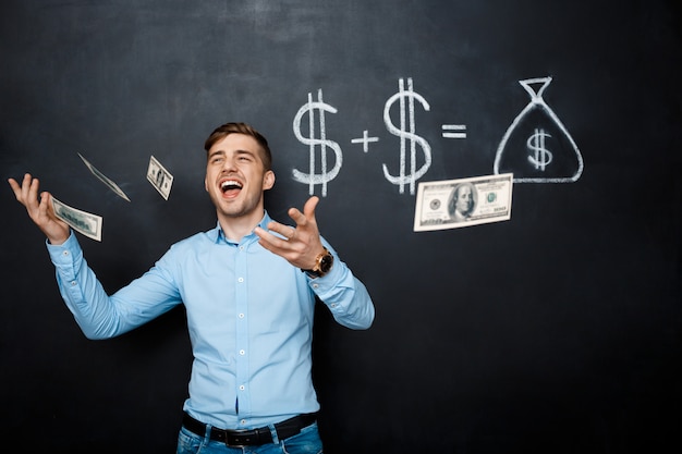 Handsome man standing over blackboard  with drawn dollar concept