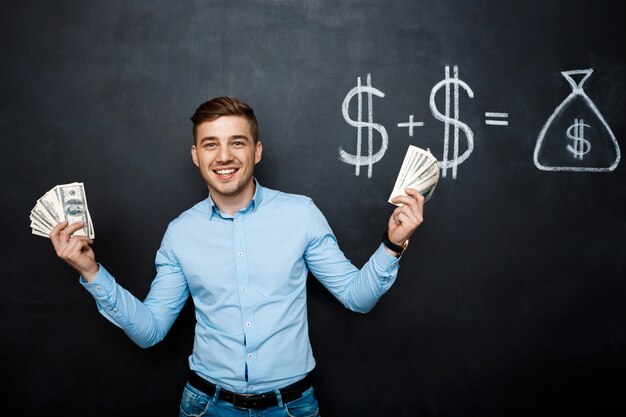 Handsome man standing over blackboard  with drawn dollar concept