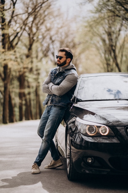 Handsome man standing by the car in the park