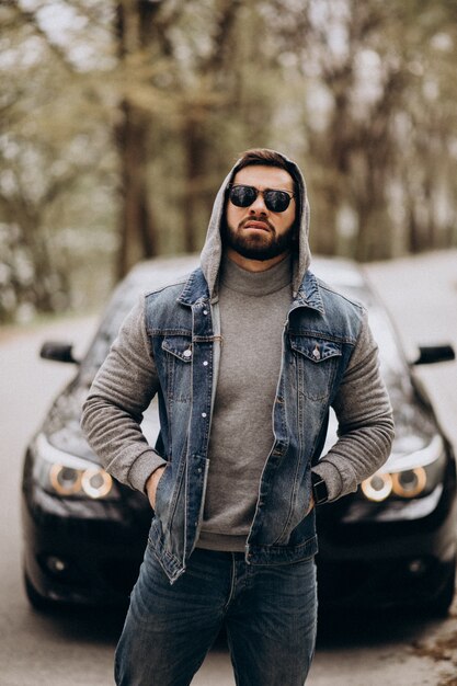 Handsome man standing by the car in the park