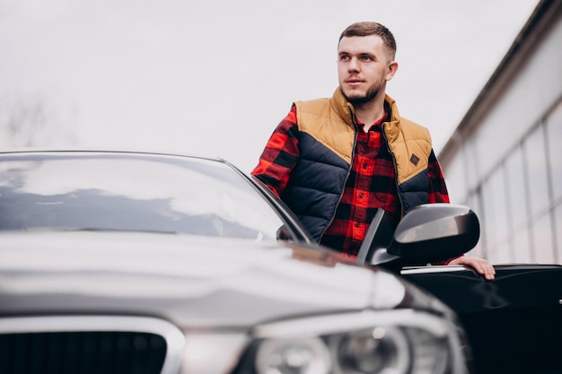 Free photo handsome man standing by the car