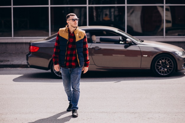 Free photo handsome man standing by the car