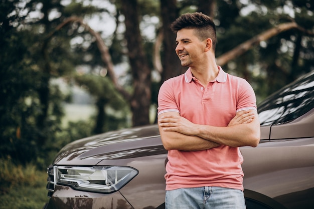 Foto gratuita uomo bello che fa una pausa la sua automobile nella foresta