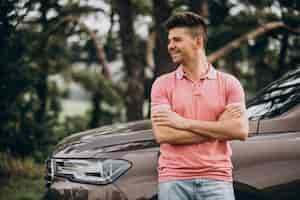 Free photo handsome man standing by his car in the forest