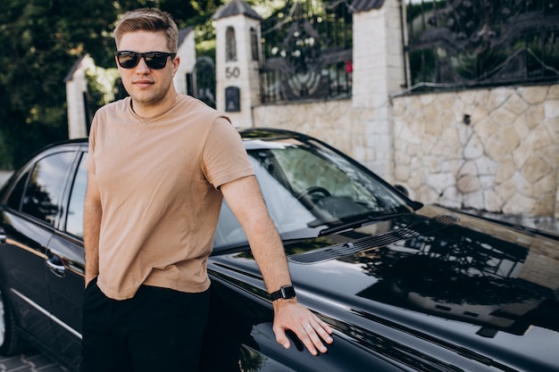 Free photo handsome man standing by his car