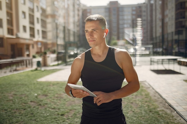 Handsome man standing in a park with earphones and a tablet