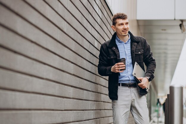 Handsome man standing in the street and holding laptop