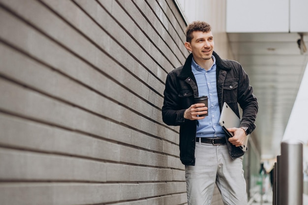 Handsome man standing in the street and holding laptop