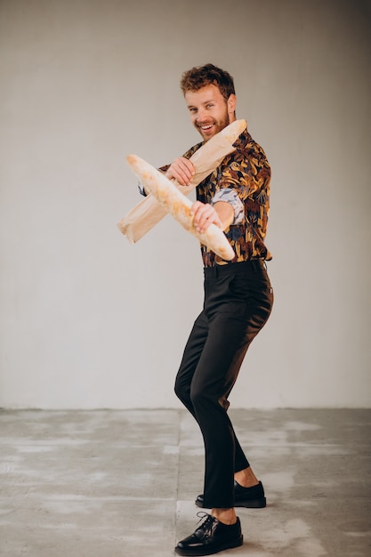 Free photo handsome man standing with french baguettes