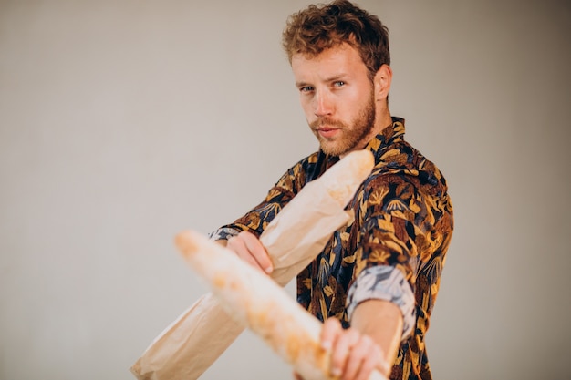 Handsome man standing with french baguettes