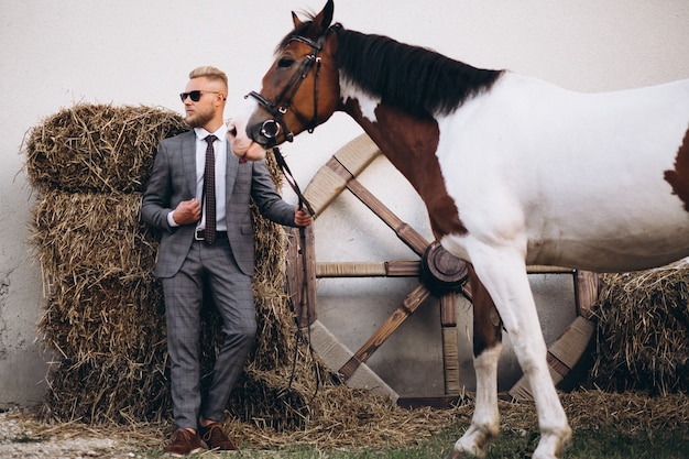 Free photo handsome man in suit at ranch by horse