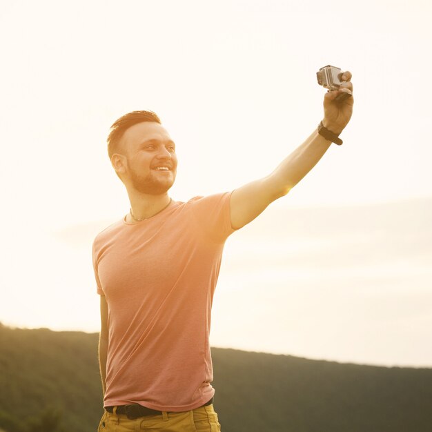 Handsome man taking pictures of him self with action camera. Retro vintage instagram filter